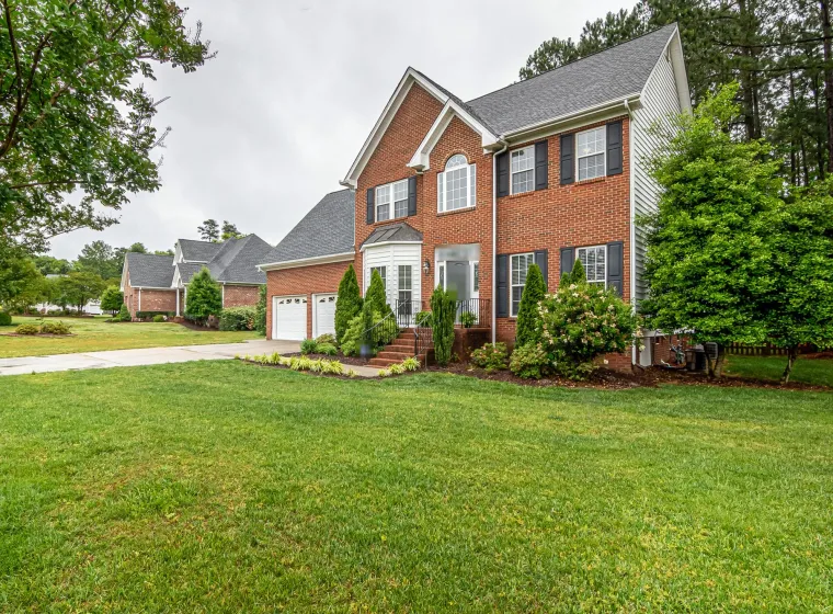 Two-story brick family home with a two-car garage and a wide front lawn